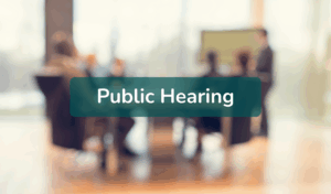 Blurred board meeting background with text overlay "public hearing"
